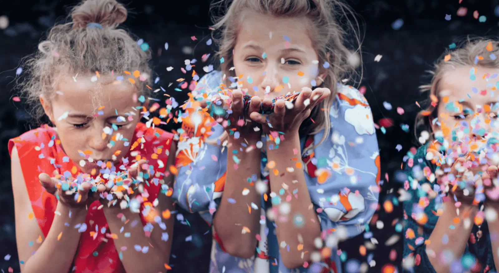 Drei Kinder pusten in Konfetti
