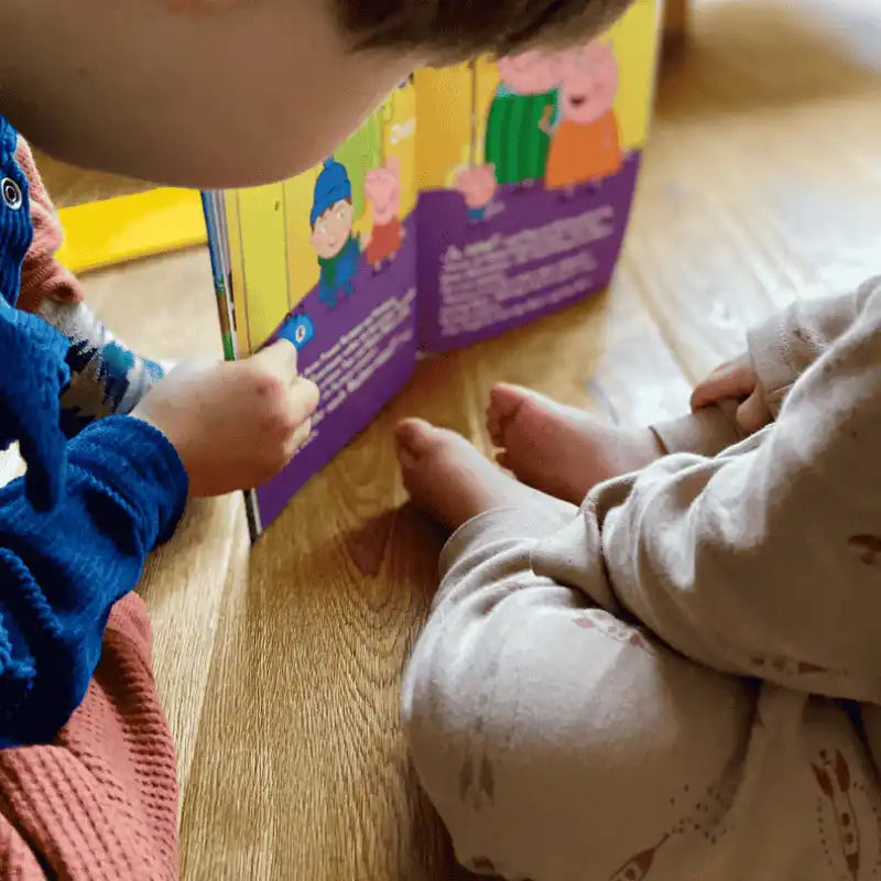 Zwei Kinder sehen sich ein personalisiertes Kinderbuch von Peppa Wutz an