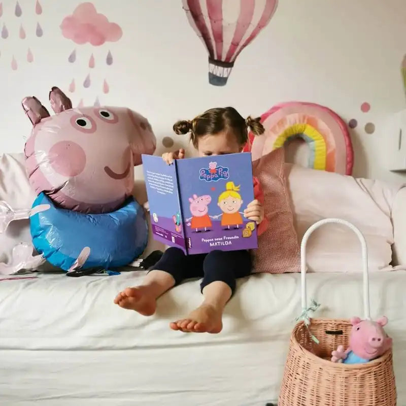 Ein kleines Mädchen liest ein Peppa Wutz Buch