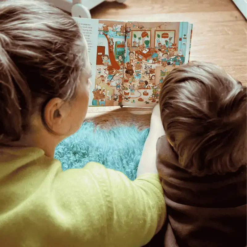 Kind und Mutter sitzen auf dem Boden und schauen sich gemeinsam ein Wimmelbuch an